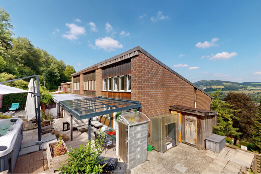 view of property featuring a hot tub, a patio, and brick siding