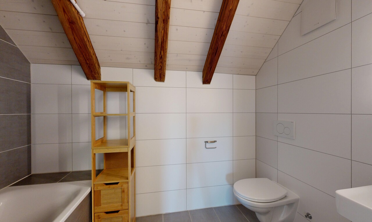salle de bains avec plafond voûté, toilette, mur en carrelage, bain, et plafond à poutres
