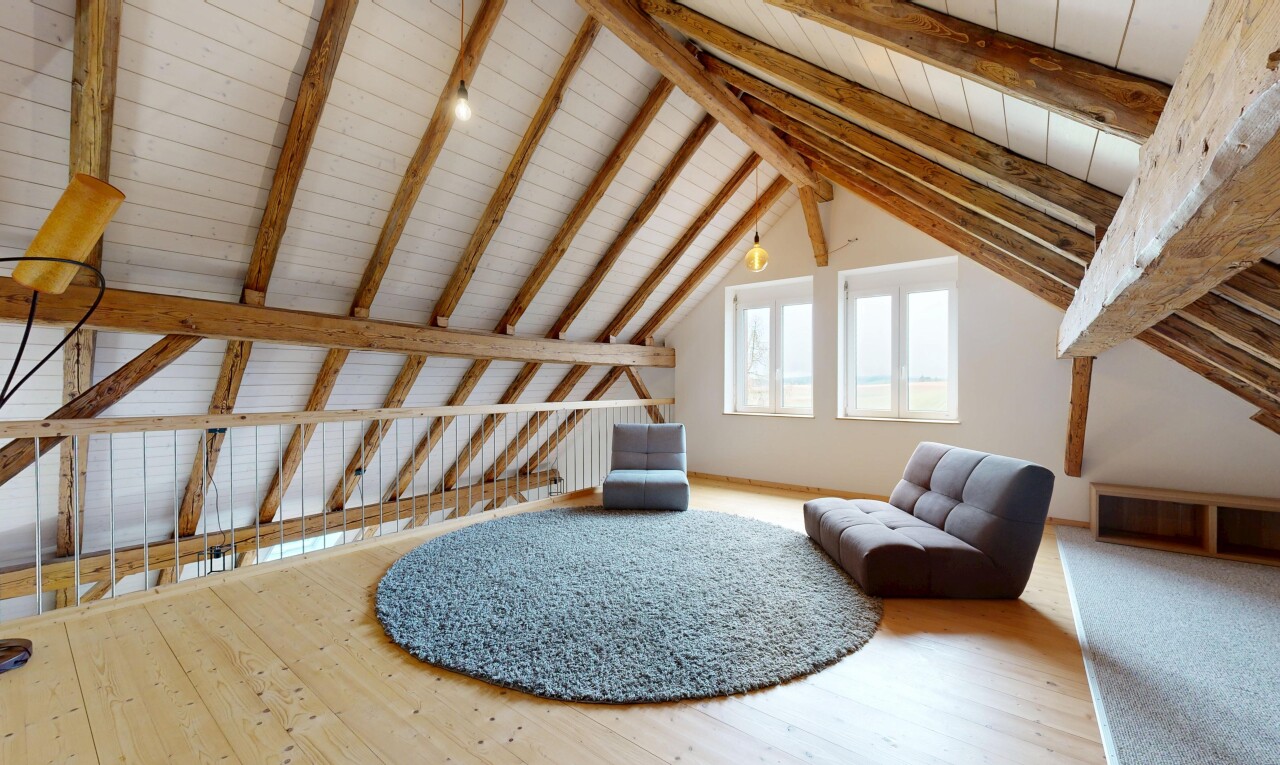 espace intérieur avec lumière naturelle, sol en finition bois, plafond à poutres, et plafond voûté