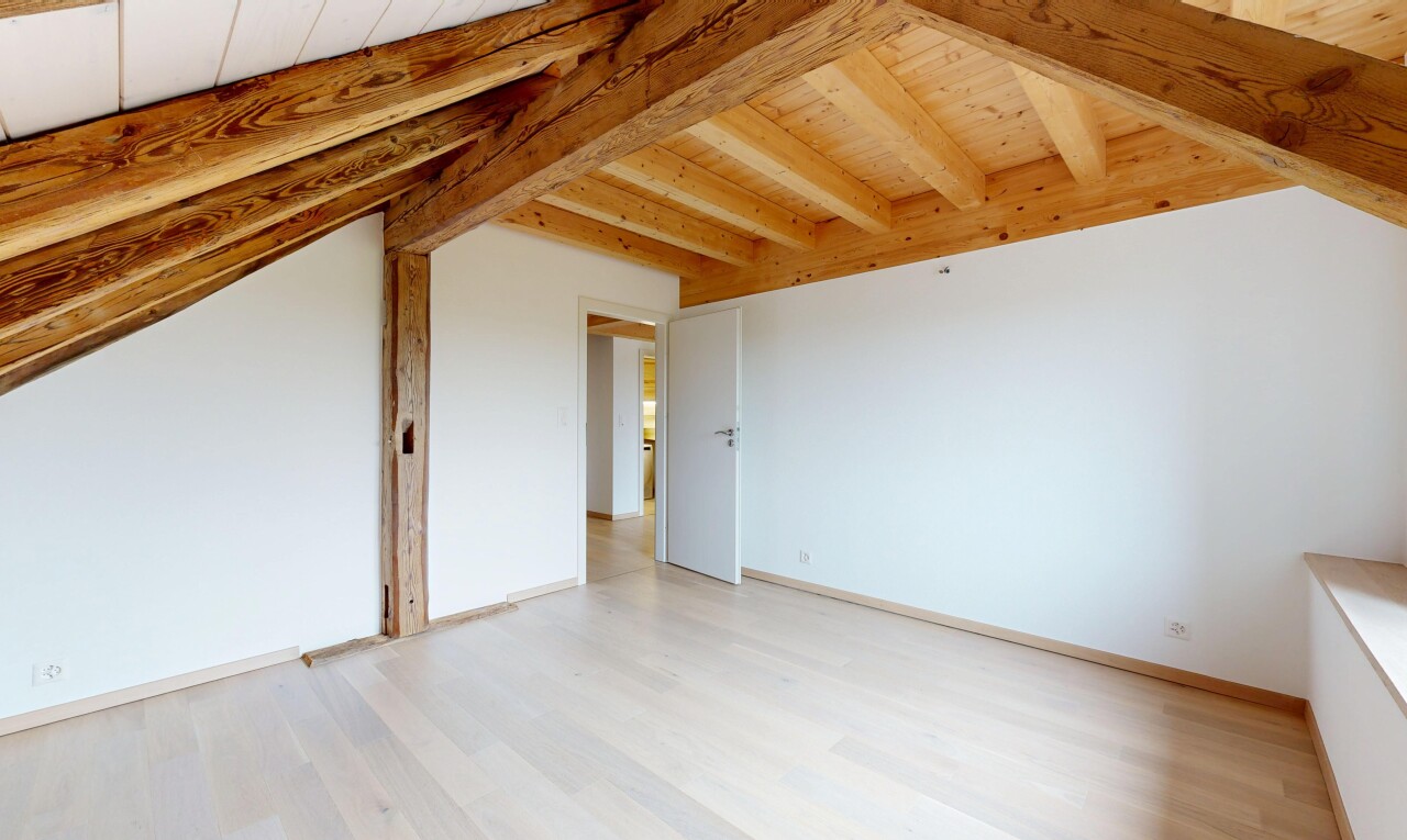 pièce vide avec sol en finition bois, plafond en bois, plafond à poutres, et cloison sèche