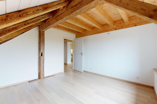 pièce vide avec sol en finition bois, plafond en bois, plafond à poutres, et cloison sèche