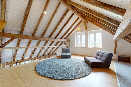 espace intérieur avec lumière naturelle, sol en finition bois, plafond à poutres, et plafond voûté