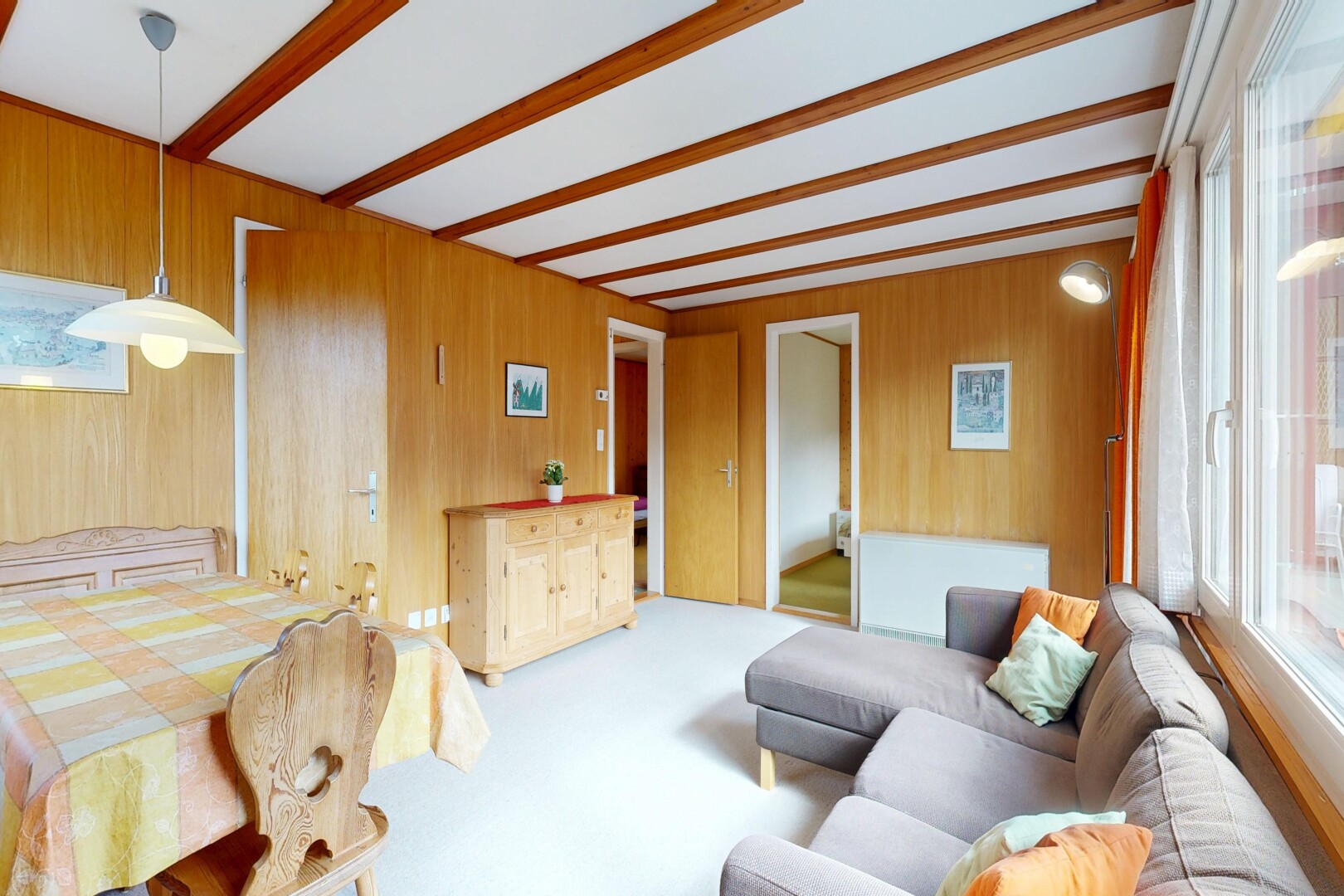 carpeted living room with beamed ceiling and wood walls