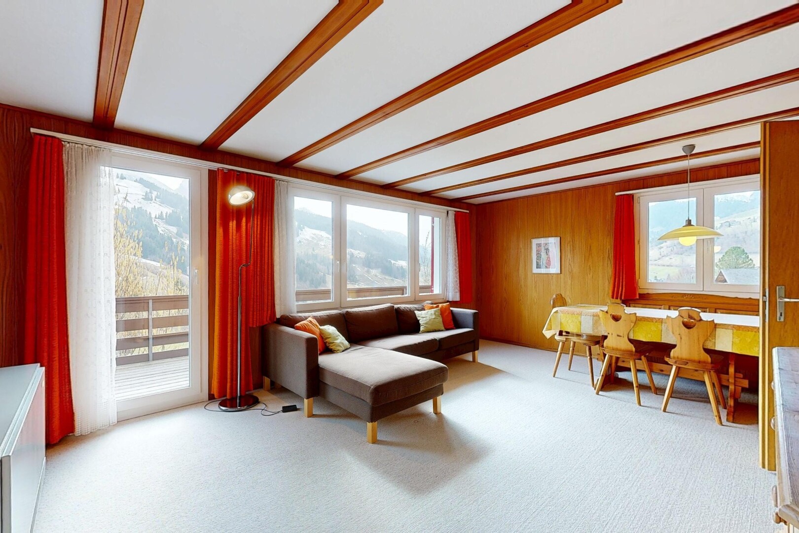 living / dining room with light colored carpet, beamed ceiling, and wooden walls