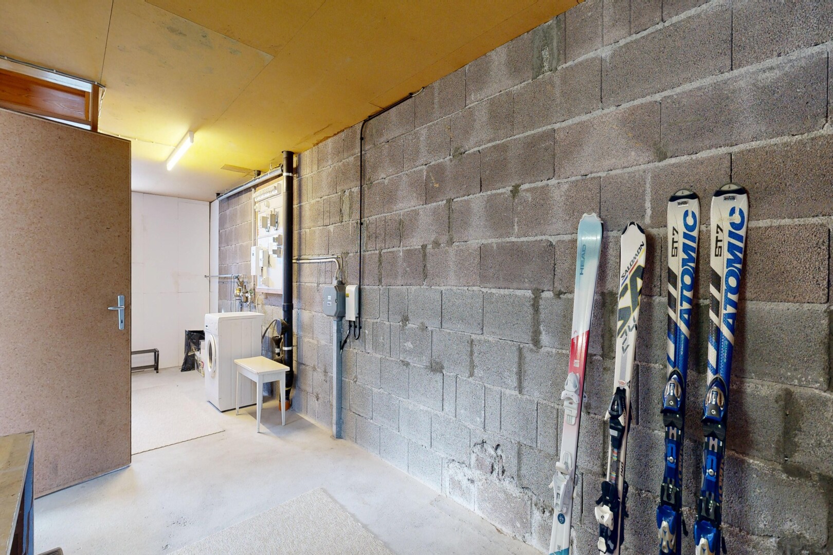 interior space with concrete block wall, unfinished concrete floors, and washer / dryer