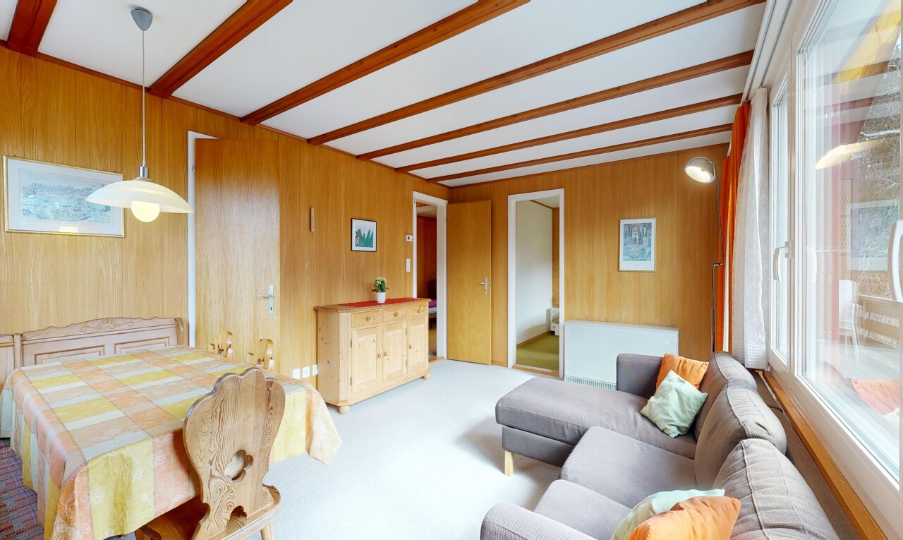carpeted living room with beamed ceiling and wood walls