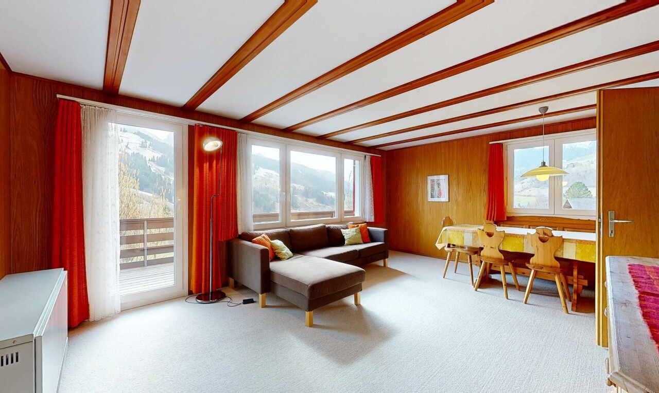 living / dining room with light colored carpet, beamed ceiling, and wooden walls