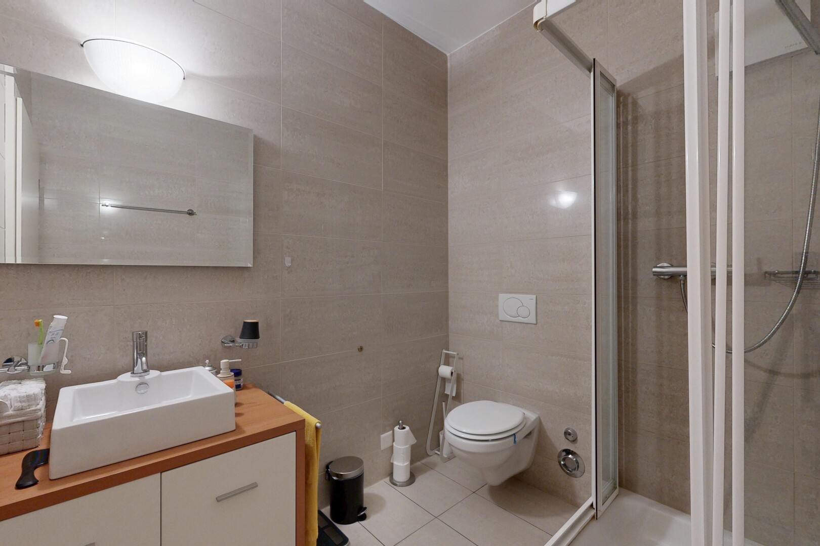 full bathroom with tile walls, a stall shower, vanity, and light tile patterned floors