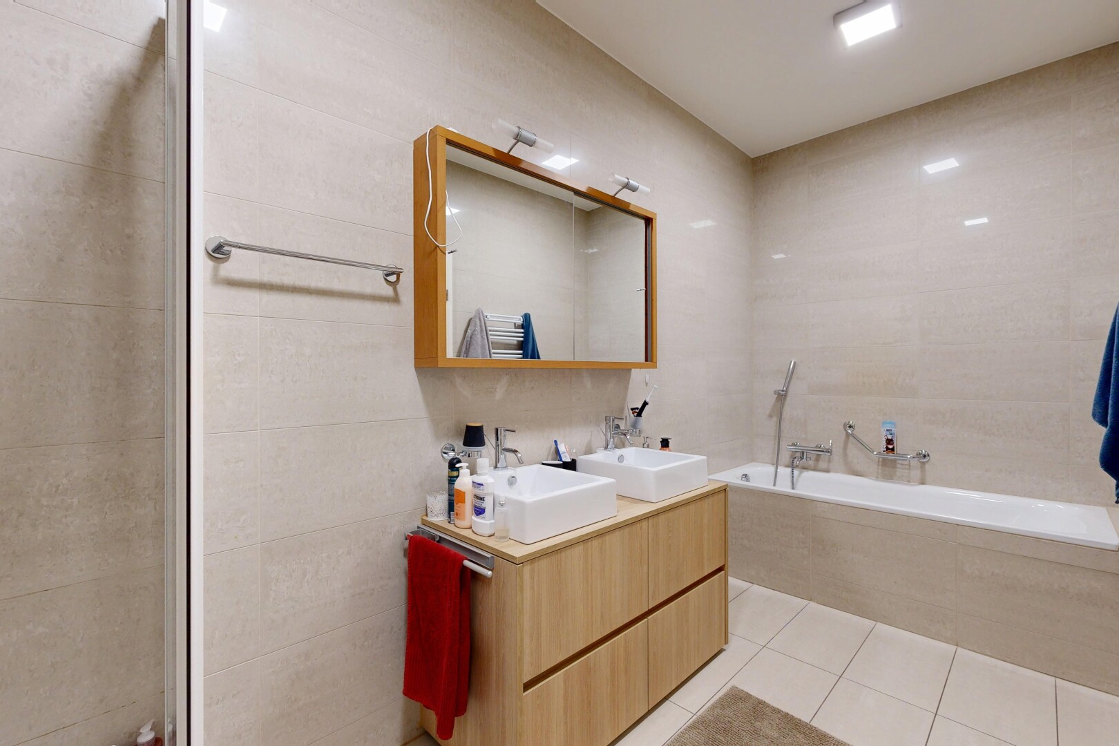bathroom featuring double vanity, tile walls, light tile patterned floors, and a garden tub
