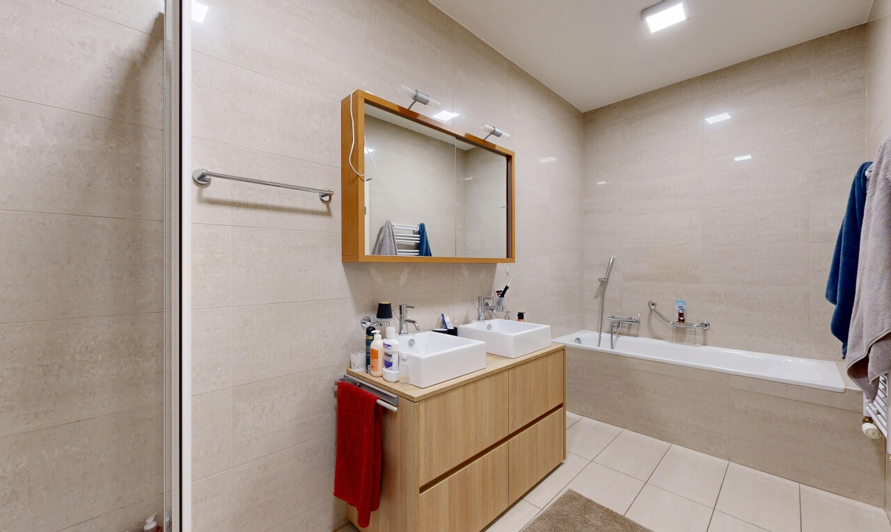 bathroom featuring double vanity, tile walls, light tile patterned floors, and a garden tub