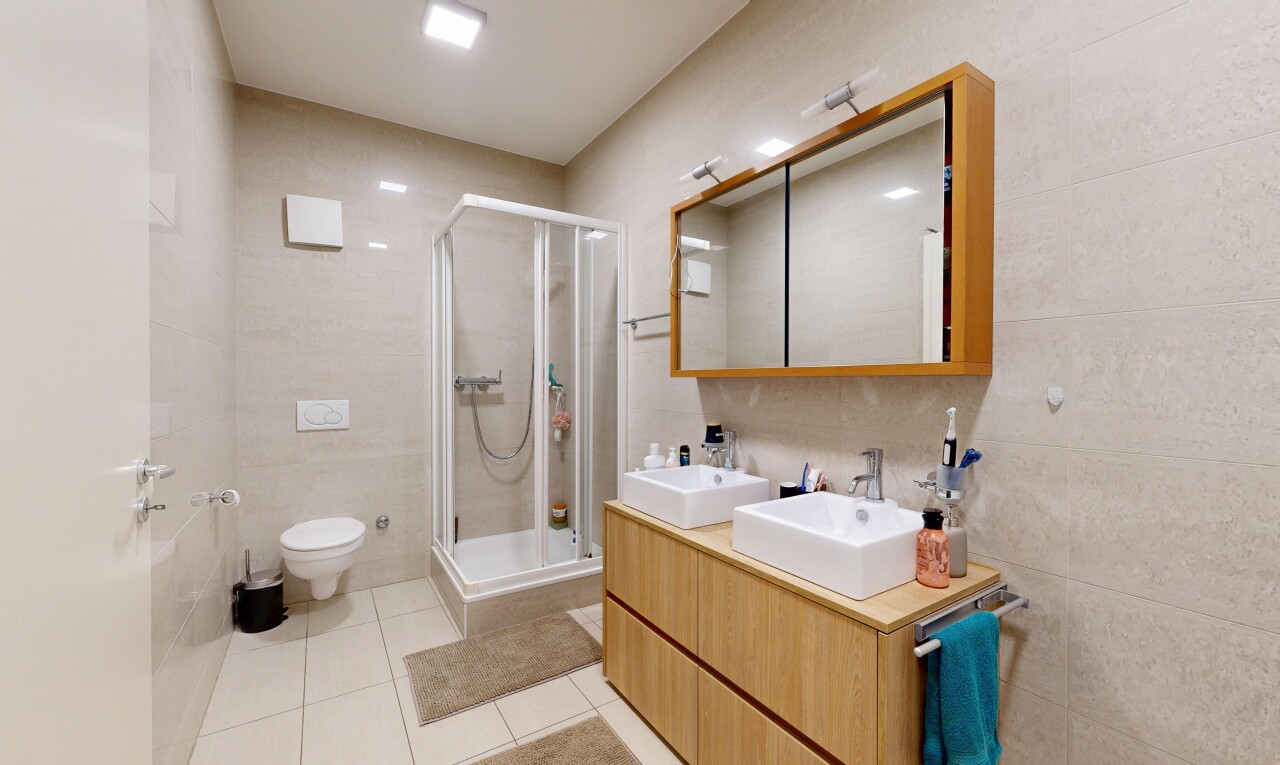 bathroom with a shower stall, tile walls, double vanity, and light tile patterned flooring