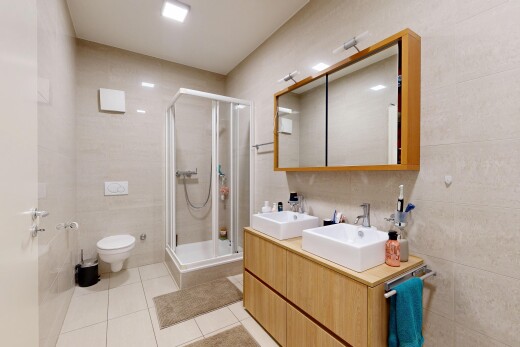 bathroom with a shower stall, tile walls, double vanity, and light tile patterned flooring