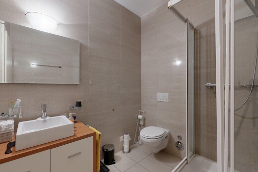 full bathroom with tile walls, a stall shower, vanity, and light tile patterned floors