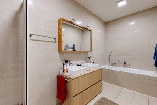 bathroom featuring double vanity, tile walls, light tile patterned floors, and a garden tub