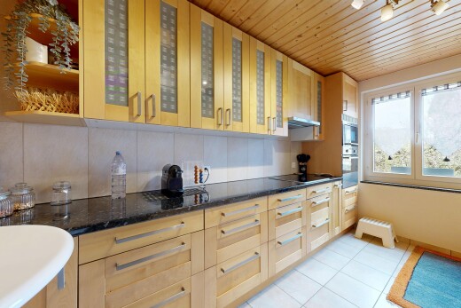 kitchen featuring light wood finish cabinets, glass fronted cabinets, dark stone counters, light tile patterned flooring, and wood ceiling
