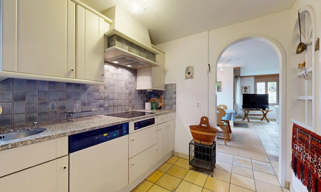kitchen featuring arched walkways, white dishwasher, light tile patterned floors, and cream cabinetry