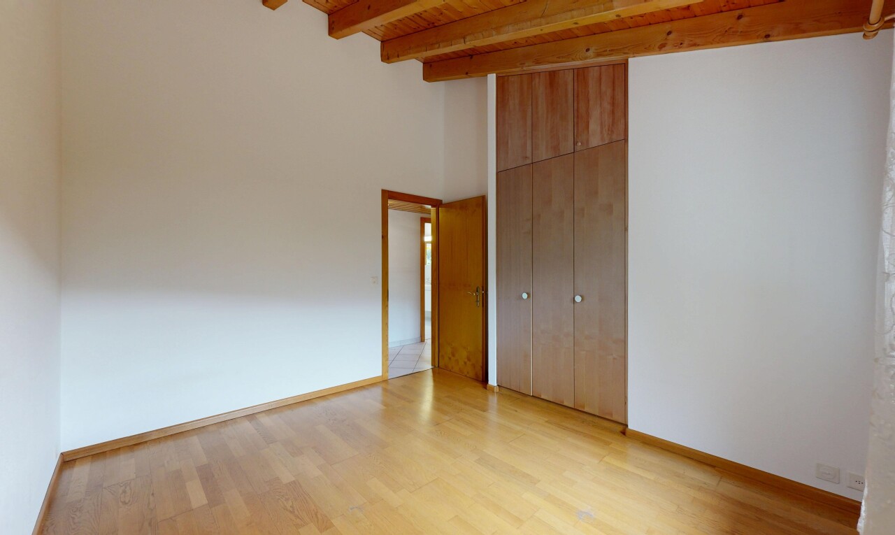 pièce vide avec plafond haut, high ceiling, sol en finition bois, wood finish floor, et plafond à poutres