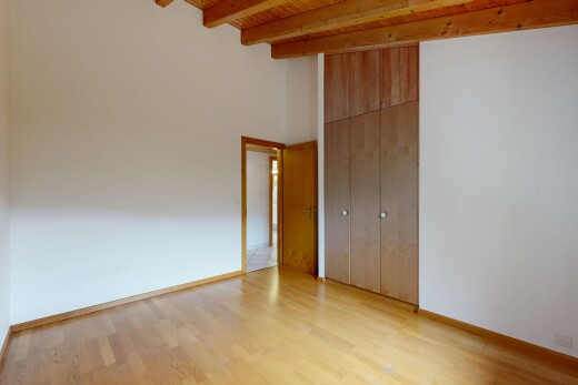 pièce vide avec plafond haut, high ceiling, sol en finition bois, wood finish floor, et plafond à poutres
