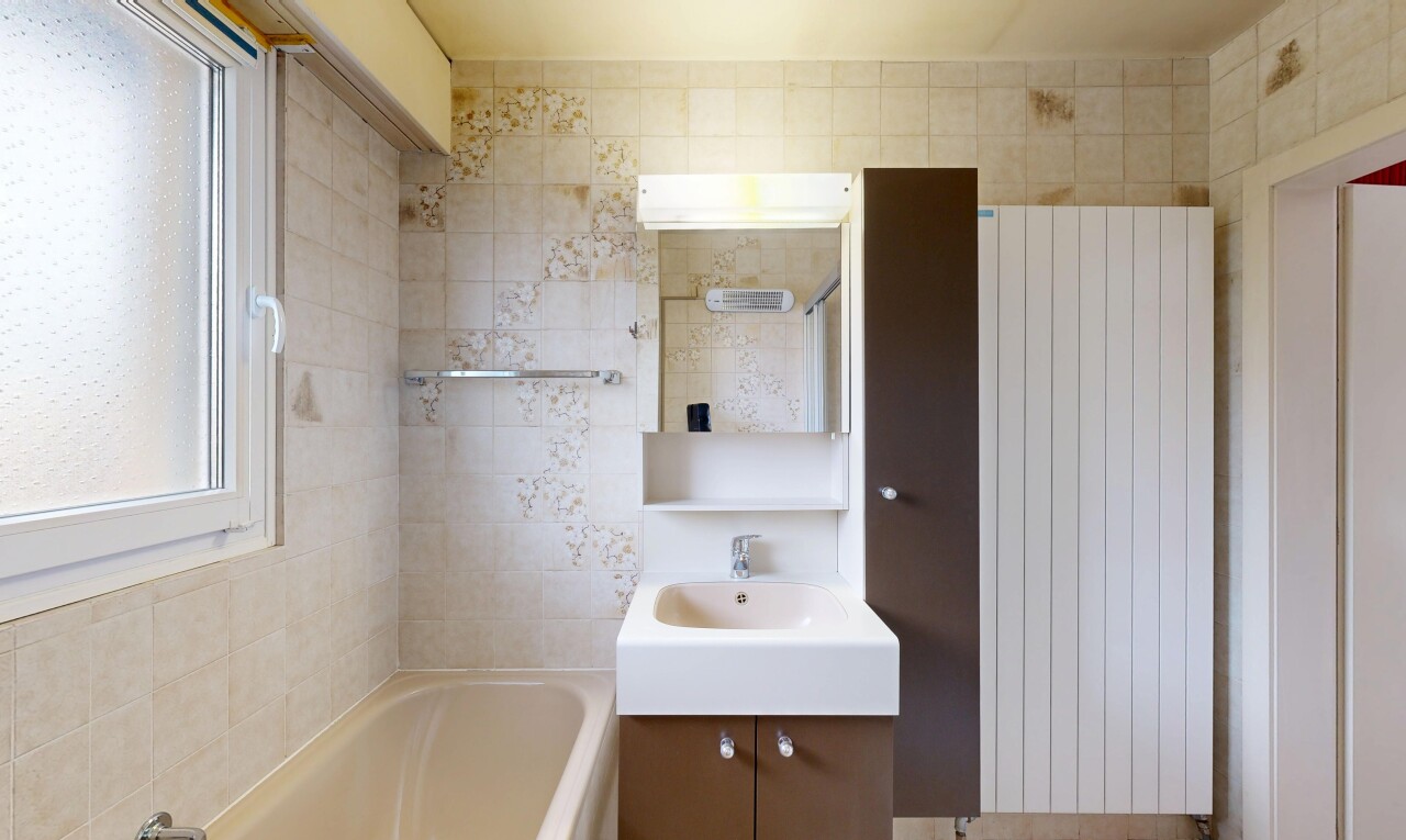 salle de bains avec salle de bain complète, bain, miroir, lavabo (ou coiffeuse selon le contexte), et radiateur