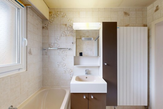 salle de bains avec salle de bain complète, bain, miroir, lavabo (ou coiffeuse selon le contexte), et radiateur