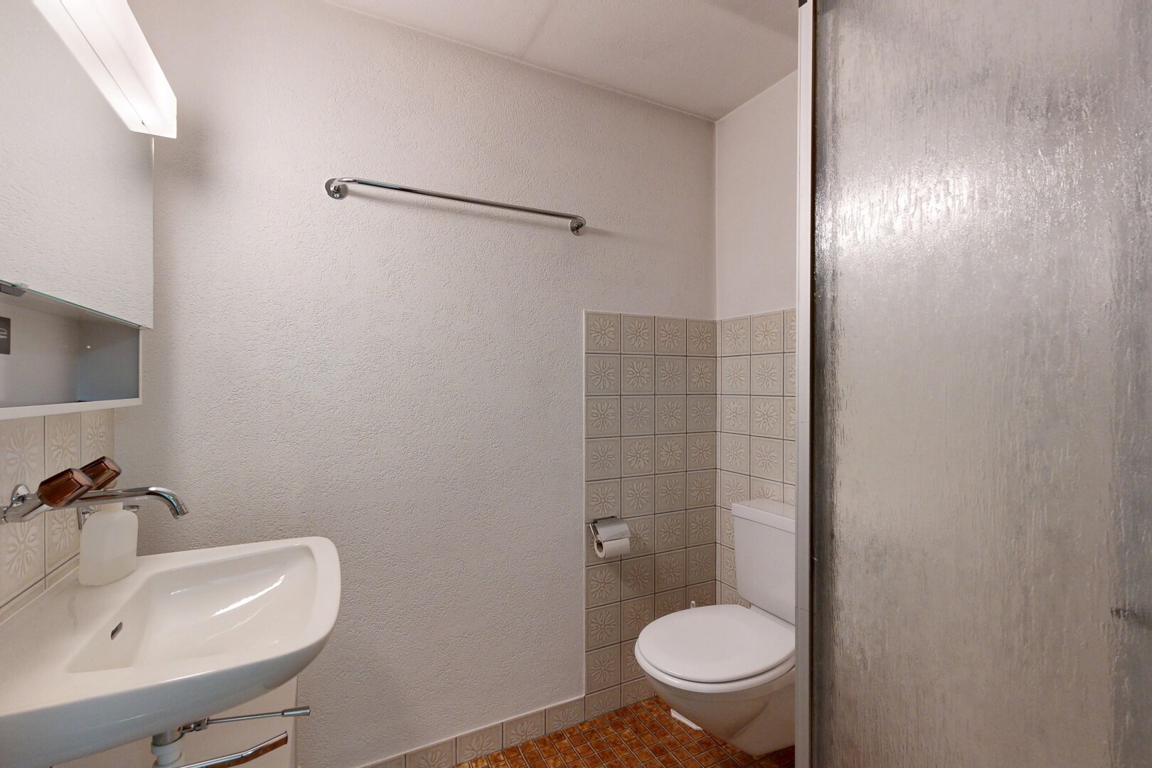 bathroom featuring a shower with door, tasteful backsplash, and a textured wall