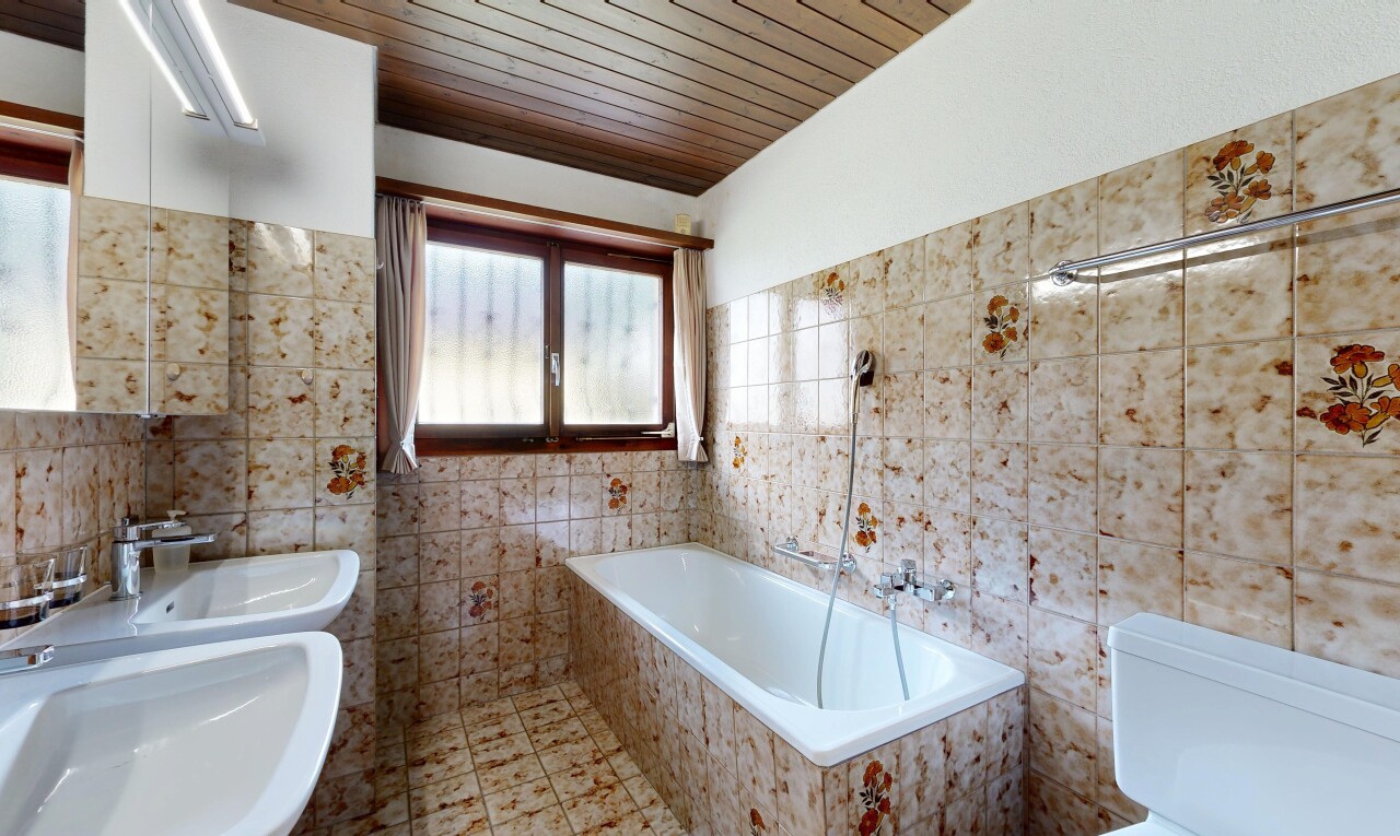 bathroom with a garden tub, wood ceiling, and tile walls