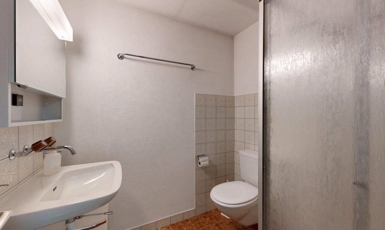 bathroom featuring a shower with door, tasteful backsplash, and a textured wall