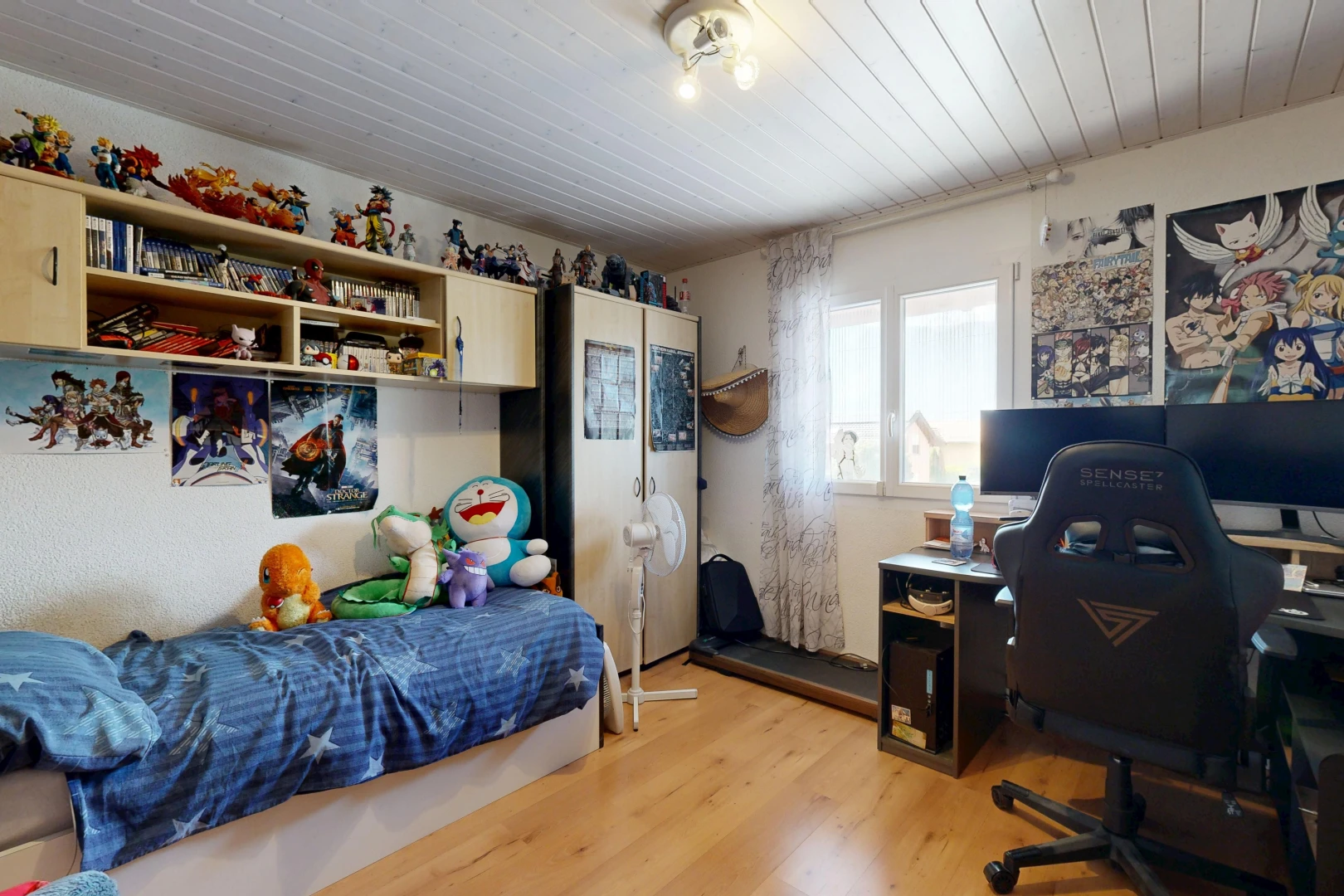 chambre avec télévision, wood finish floor, sol en finition bois, espace bureau, et étagères intégrées
