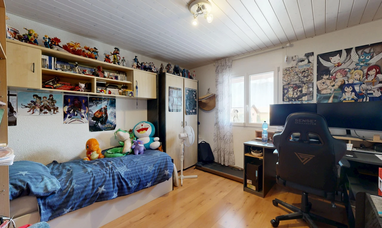 chambre avec télévision, wood finish floor, sol en finition bois, espace bureau, et étagères intégrées