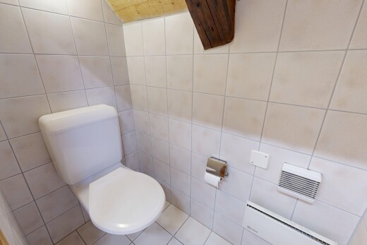 salle de bains avec toilette, radiateur à plinthe, tile wall, mur en carrelage, et inside property