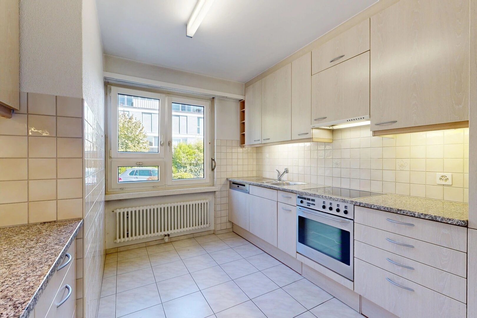 cuisine avec light countertops, stone countertops, plans de travail en pierre, radiateur, et four