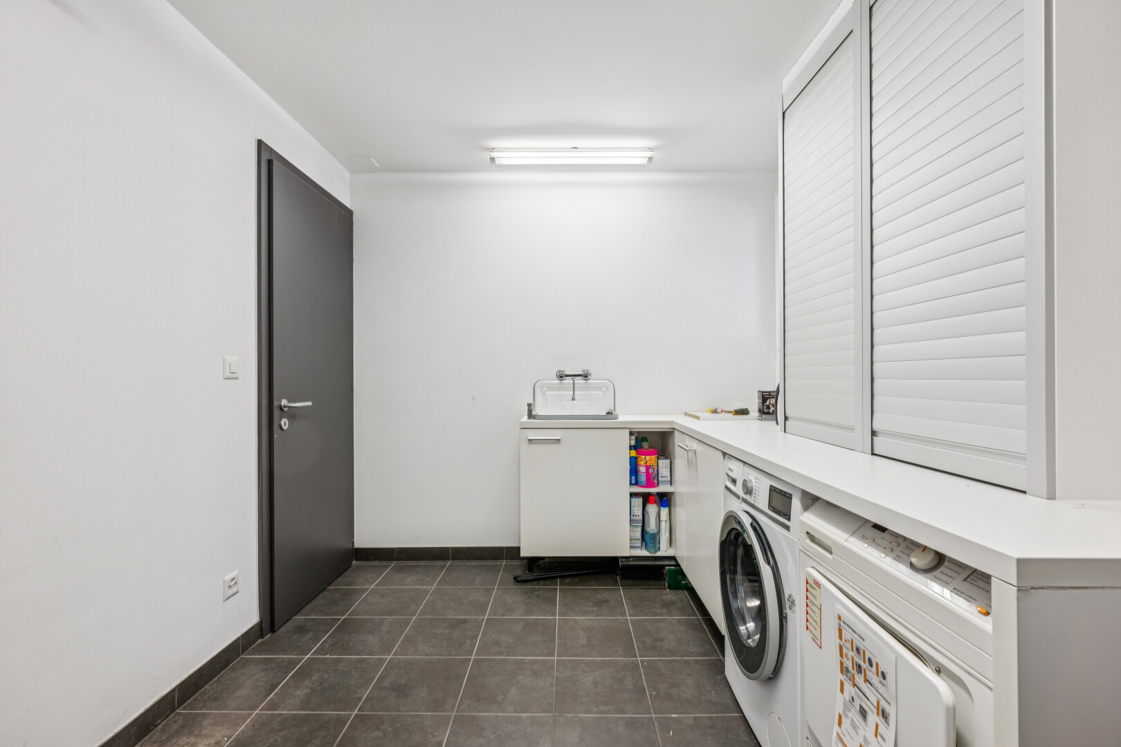 wäschekammer mit dark floor, drywall, gipskartonwand, tile floor, und fliesenboden