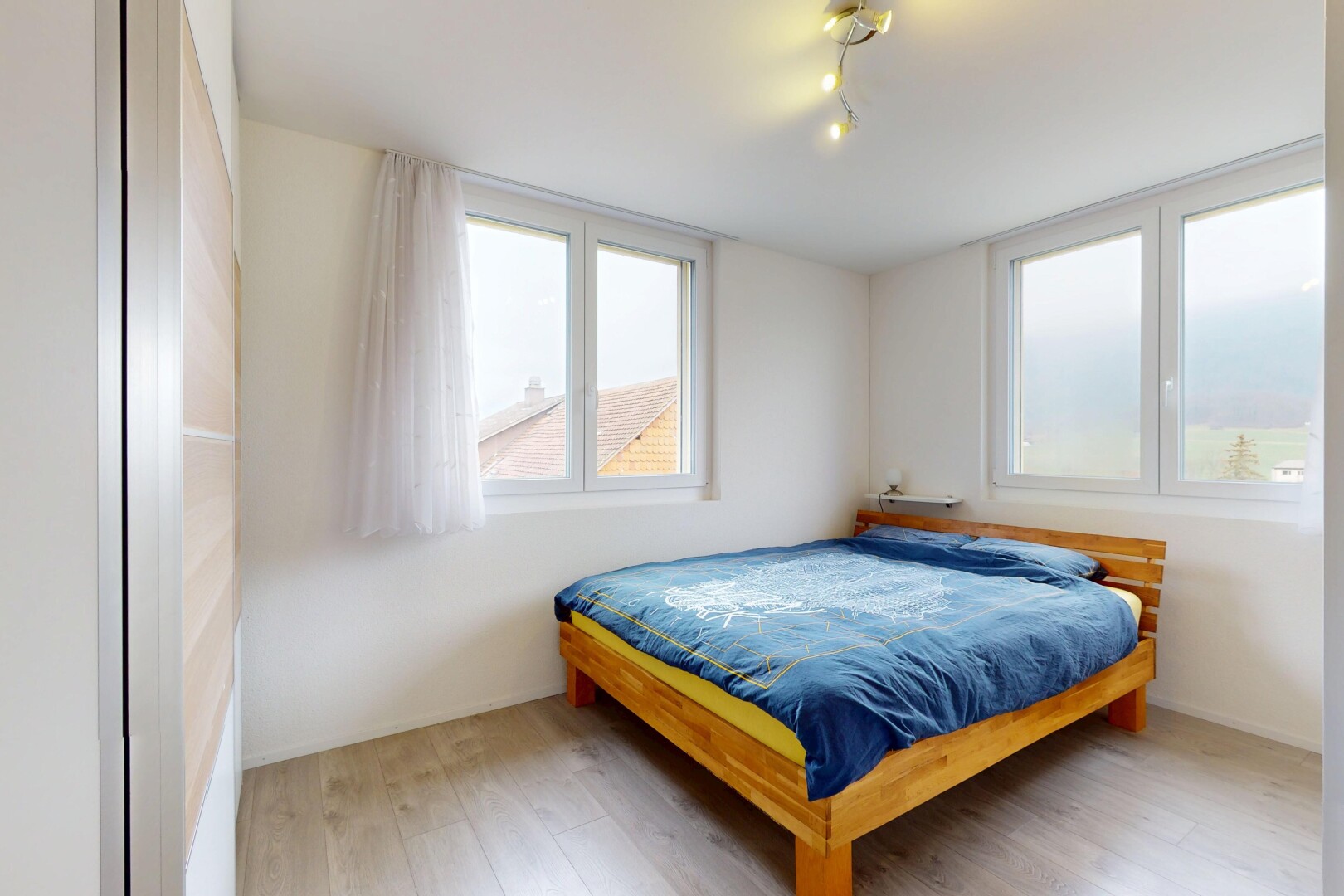 chambre avec sol en finition bois, lumière naturelle, éclairage sur rail, et cloison sèche