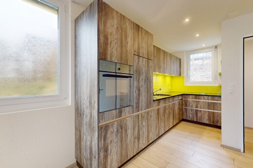 cuisine avec four, lumière naturelle, plans de travail, sol en finition bois, et armoires à panneau plat