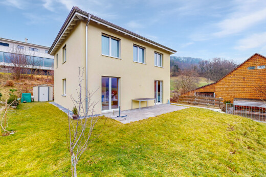 façade avec bardage en stuc, terrasse, property visible, clôture, et pelouse