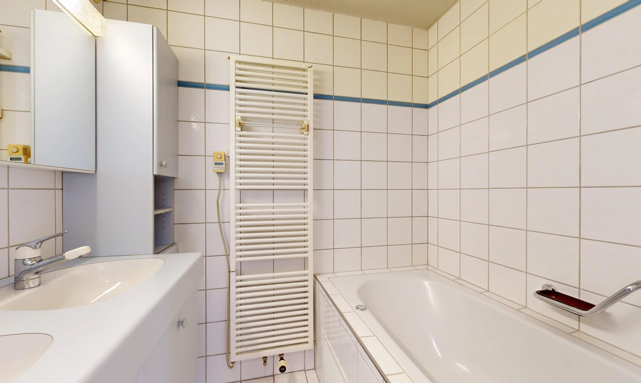 salle de bains avec radiateur, chauffe-serviettes, salle de bain complète, évier, et mur en carrelage