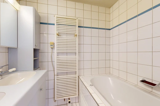 salle de bains avec radiateur, chauffe-serviettes, salle de bain complète, évier, et mur en carrelage