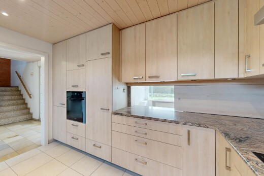 küche mit fliesenboden, hellbraune schränke, ofen, und stein arbeitsplatten