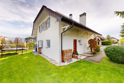 façade avec trampoline, pelouse, cheminée, bardage en stuc, et property visible