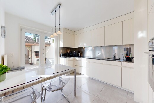 cuisine avec dosseret, backsplash, armoires à panneau plat, éclairage suspendu, et lumière naturelle