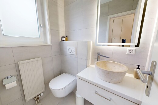 salle de bains avec radiateur, mur en carrelage, tile wall, miroir, et évier