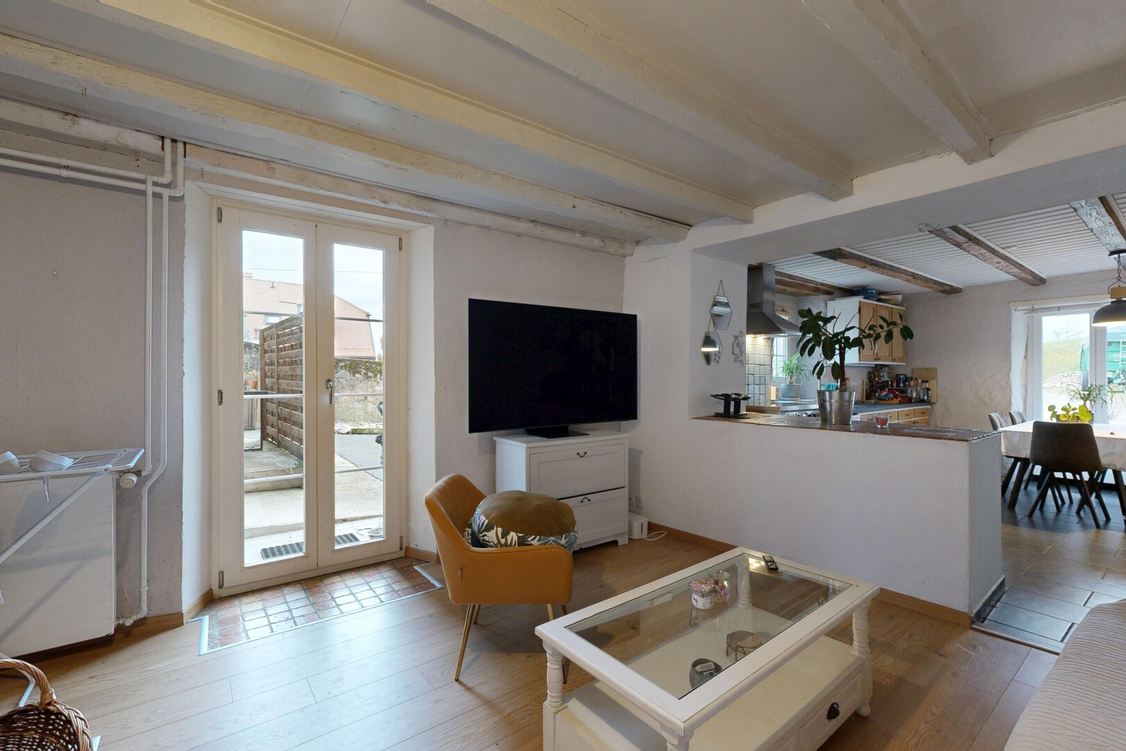 salon / salle à manger avec plafond à poutres, beamed ceiling, télévision, inside property, et lumière naturelle