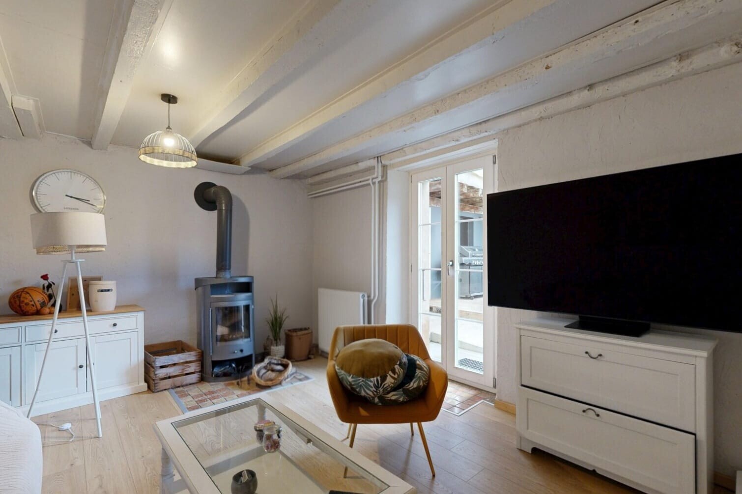 salon avec poêle à bois, télévision, lumière naturelle, natural light, et plafond à poutres