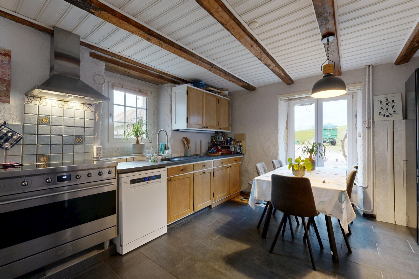 cuisine avec cuisinière, hotte, armoires de style shaker, lave-vaisselle, et lumière naturelle