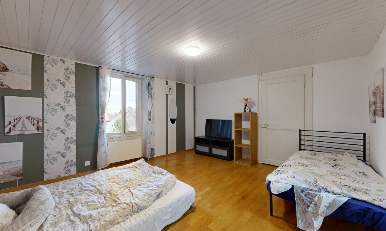chambre avec sol en finition bois, wood finish floor, télévision, lumière naturelle, et natural light