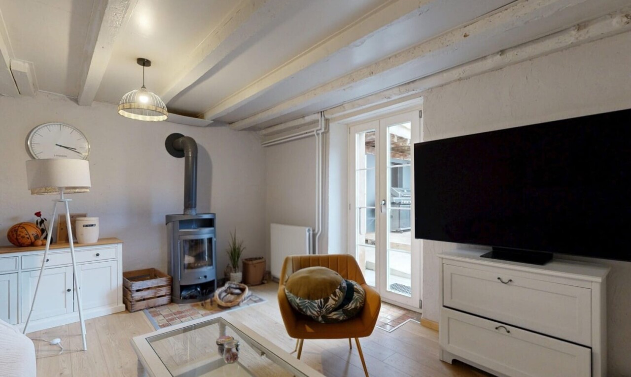 salon avec poêle à bois, télévision, lumière naturelle, natural light, et plafond à poutres