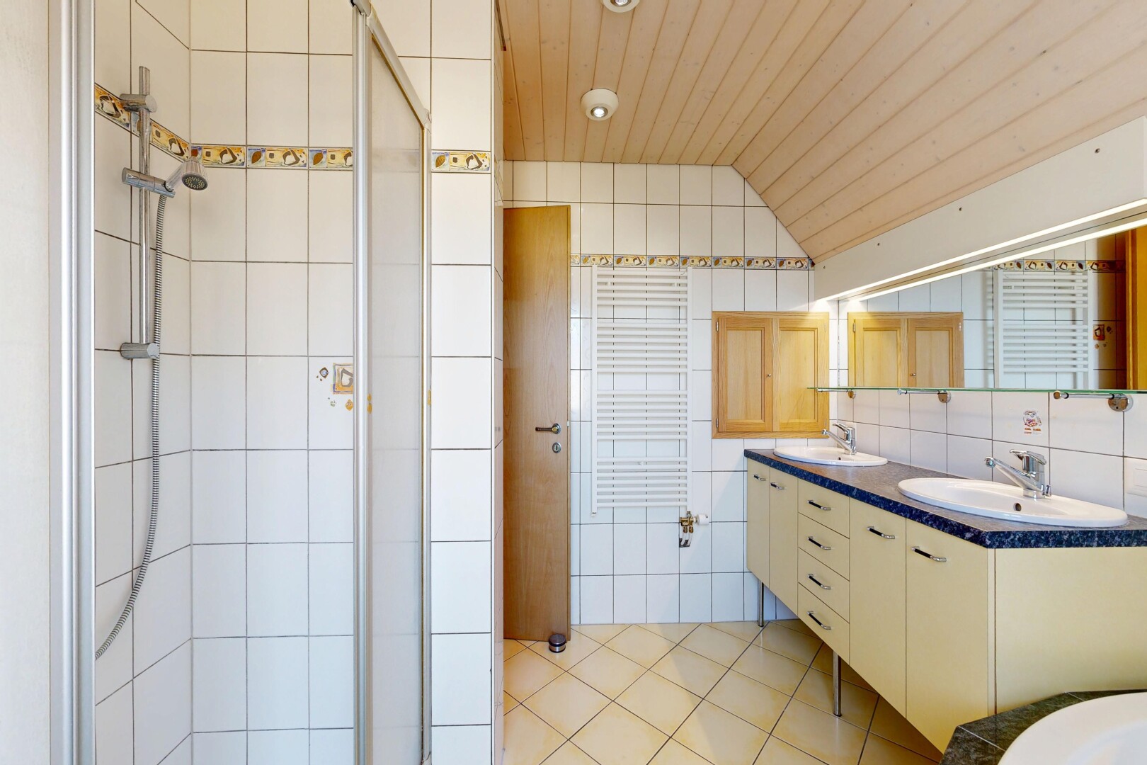 salle de bains avec douche, light floor, salle de bain complète, double vasque, et mur en carrelage