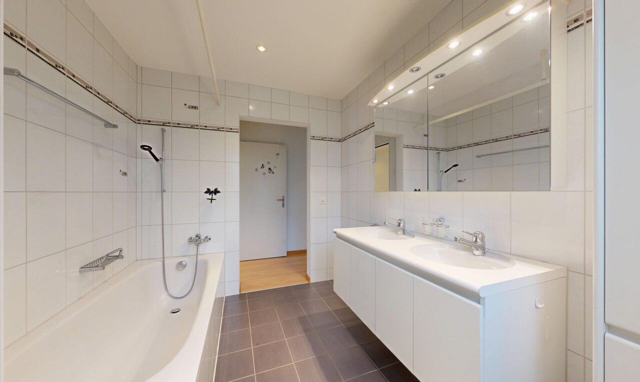 full bathroom featuring tile walls, a bath, double vanity, dark tile patterned floors, and recessed lighting