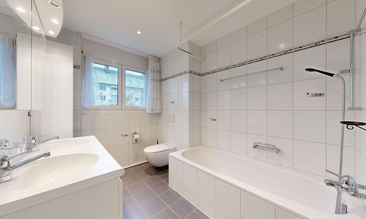 bathroom with double vanity, tile walls, dark tile patterned floors, and tiled shower / bath combo
