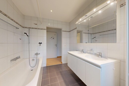 full bathroom featuring tile walls, a bath, double vanity, dark tile patterned floors, and recessed lighting
